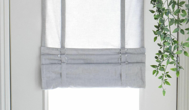 With a tiered tumble shade in St. George, you can block sun glare all year round. Gray rolled tumble shade on a glass door